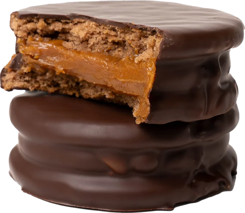 Alfajor argentino bañado en chocolate, cortado, con el dulce de leche a la vista